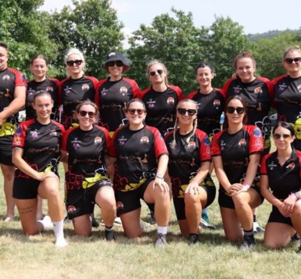 Pontardawe's women's touch rugby team kneeling together on the field in black and red kit