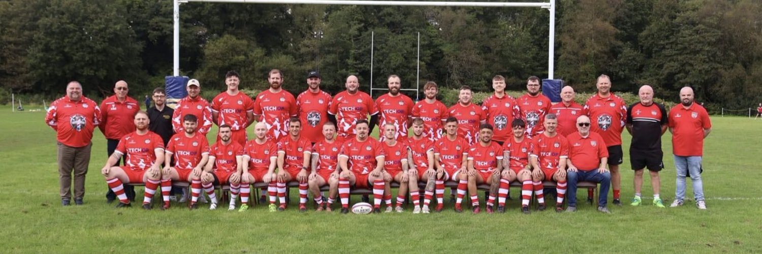 The Pontardawe RFC squad, coaches and committee line up on the pitch in the club's red and white kit, 2024
